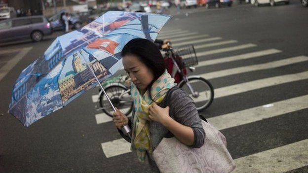 A woman protects herself from the rain with an umbrella in Beijing on 26 September 2014.