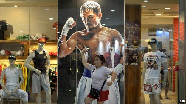 A woman poses in front of a poster of Philippine boxing icon Manny Pacquiao at a store in Manila.