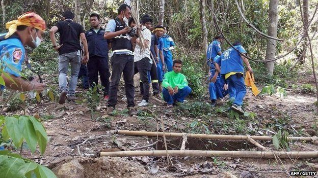 Rescue workers and forensic officials inspect the site of a mass grave uncovered at an abandoned jungle camp in the Sadao district of Thailand's southern Songkhla province bordering Malaysia on 1 May 2015.