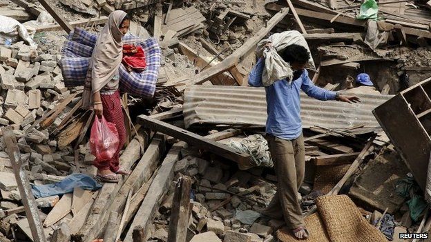 People carry their belongings as they walk on the rubble of buildings which were destroyed after last week's earthquake in Bhaktapur, Nepal, May 2, 2015.
