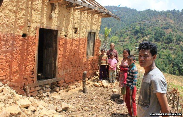 Buddhimaya's family stand outside their home, which is still standing but unsafe to enter