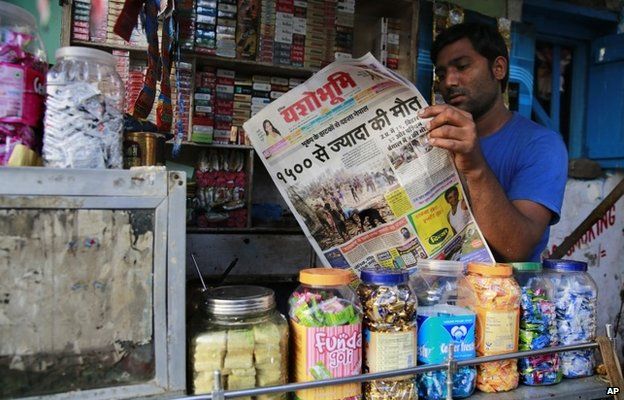 An Indian shopkeeper reads a newspaper with front-page news of Nepal earthquake in Mumbai, India, Sunday, April 26, 2015