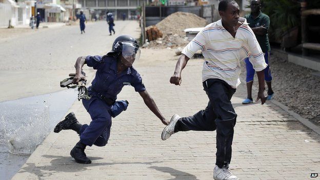 Riot police chase a demonstrator in Bujumbura, Burundi, Monday, May 4, 2015