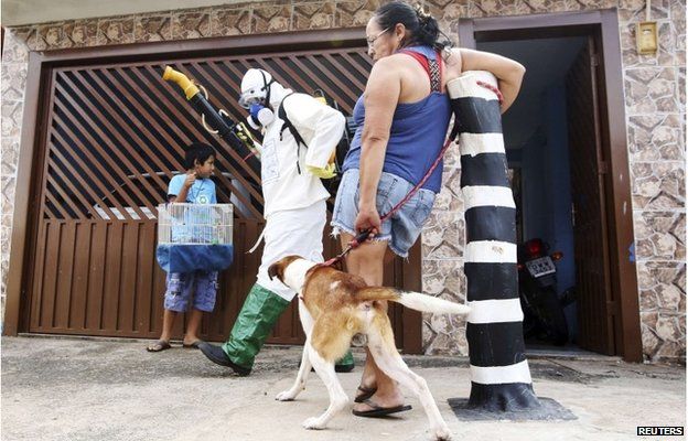 A national health official walks past residents as he carries out fumigation to help control the spread of Chikungunya and dengue fever