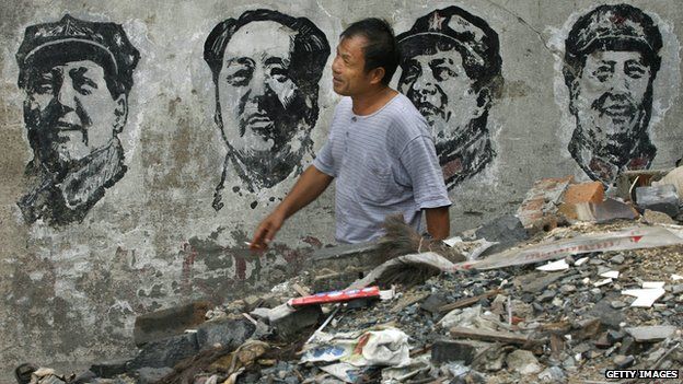 A man walks past portraits of the former Chinese leader Mao Zedong