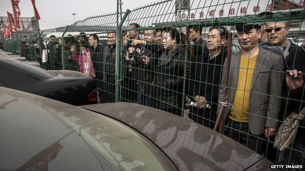 Chinese buyers wait behind a fence as they wait to hopefully enter to bid at an auction of government vehicles