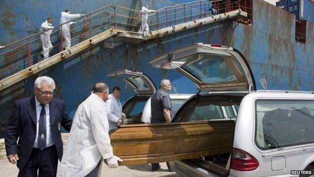 The coffin containing the body of a dead migrant from a merchant ship is put in a car after arriving at the Sicilian harbour of Catania, southern Italy, on 5 May 2015