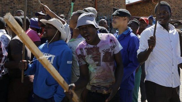 Local South African men dance and sing while carrying clubs as they call for foreign shop owners to leave the area after xenophobic violence in the area in Actonville, Johannesburg, South Africa, 16 April 2015