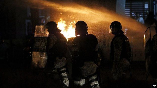 Police officers pass by burning barricades set up on a street by protesters during a protest in Skopje Macedonia, 1 May 2015.