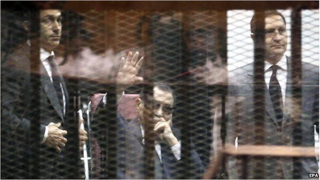 Hosni Mubarak, flanked by his sons Gamal (L) and Alaa (R), waves from the defendants' cage in Cairo, 9 May 2015.