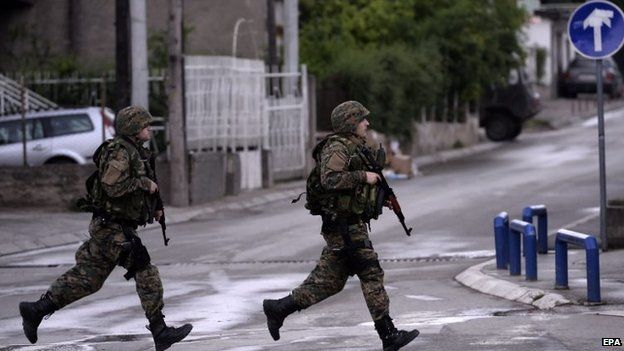 Police officers run across a street in Kumanovo, Macedonia, 9 May 2015.