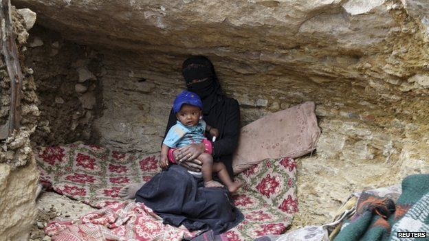 An internally displaced woman sits with a child in a cave in the district of Khamir of Yemen"s north-western province of Amran 9 May 2015