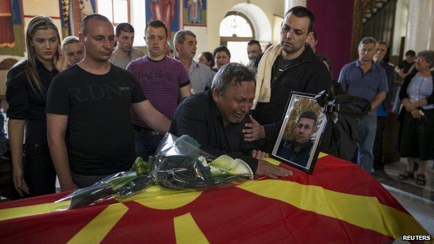 Relatives of killed policeman Sasho Samoilovski mourn next to his coffin covered in Macedonian flag inside a church in town of Tetovo, Macedonia, on 10 May 2015.