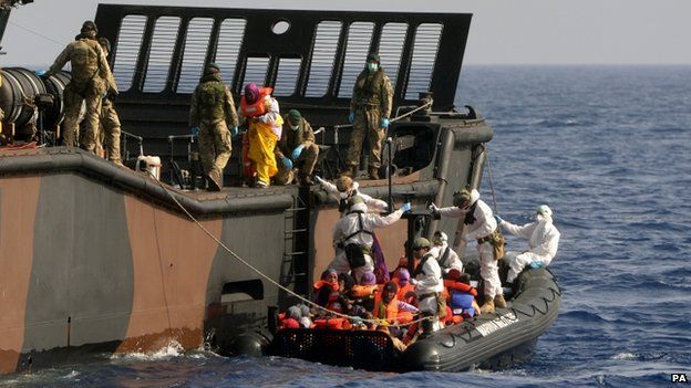 HMS Bulwark staff help refugees adrift in the Mediterranean onto a Royal Navy Landing Craft in the Mediterranean taken on 7 May 2015