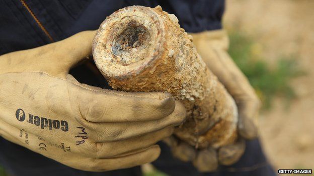 Mine-clearing specialist Guy Momper holds an unexploded German 70mm artillery shell from World War I found by a local farmer in a field at Champneuville on August 26, 2014 near Verdun, France