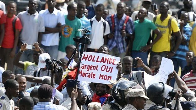 Protesters in Port-au-Prince hold a banner that reads: "Hollande: Money Yes, Morals No"