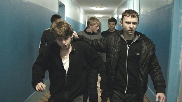 Still from The Tribe - a group of young men striding down a blue corridor