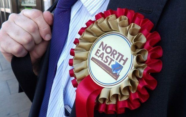 A man wearing a North East rosette