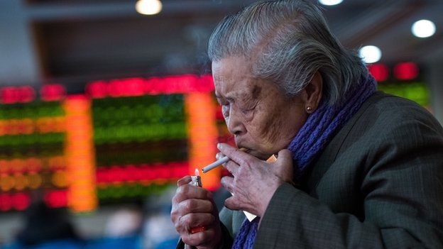A man lighting a cigarette inside a stocks trading hall