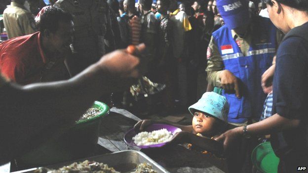 Mostly Rohingya migrant women and children are served a ration by government social welfare personnel in Aceh province, Indonesia (14 May 2015)
