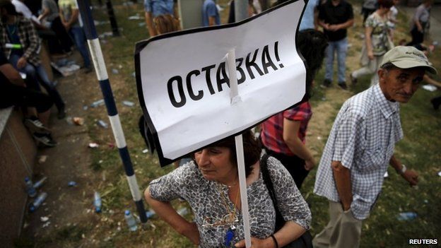 A protester holds a sign that says "resign" in Skopje on 17 May