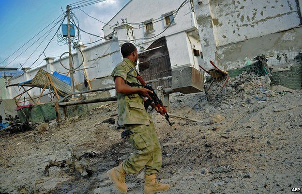 A solder walks past at the scene of a car bomb attack and armed raid by al-Shabab militants on the Maka al Mukarama hotel in Mogadishu 27 March 2015.