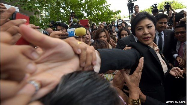Yingluck Shinawatra shakes hands with her supporters outside the Supreme Court in Bangkok