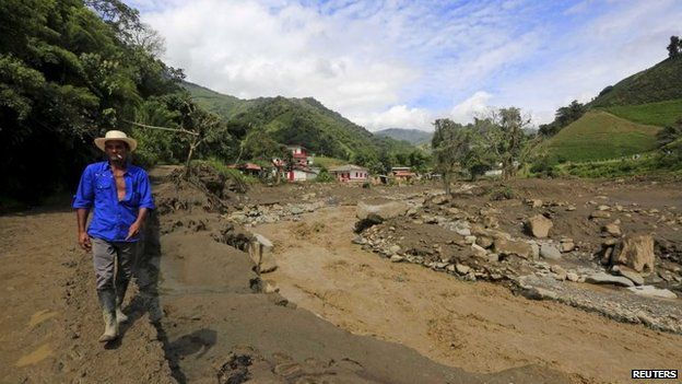 A resident walks in front of houses that were destroyed after a landslide sent mud and water crashing onto homes in Salgar on 19 May, 2015.