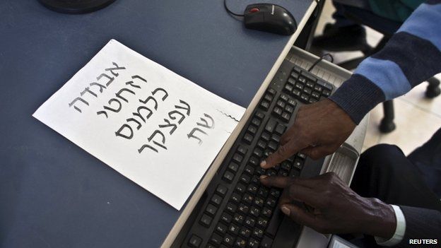 A Hebrew teacher (right), an Israeli of Ethiopian descent, shows a new immigrant from Ethiopia letters on a keyboard at an absorption centre for new immigrants near Jerusalem