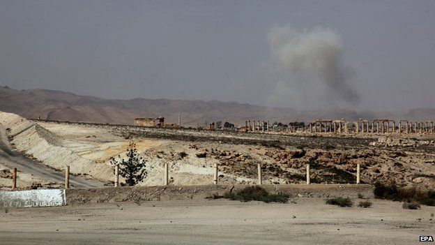 Smoke rises after a Syrian Rocket launcher shell on enemy positions in the ancient oasis city of Palmyra on 19 May
