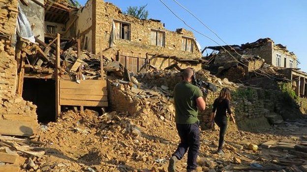 Reporter Yalda Hakim and camera operator walk through the rubble of a village in Nepal