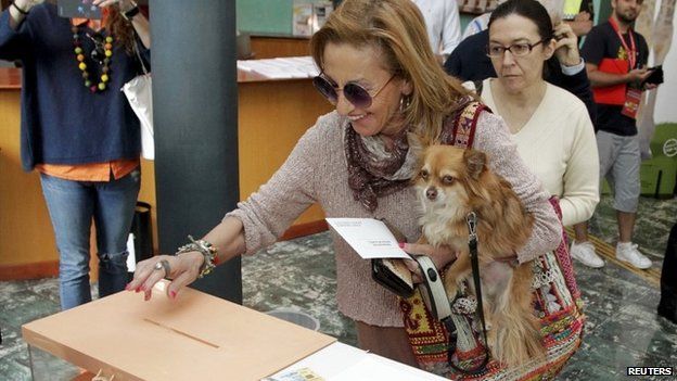 A woman holding a dog votes in Spain's local elections