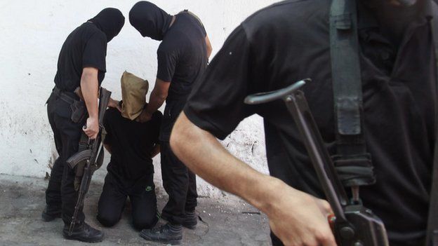 Hamas militants hold a Palestinian suspected of collaborating with Israel before he is executed in Gaza (August 2014)
