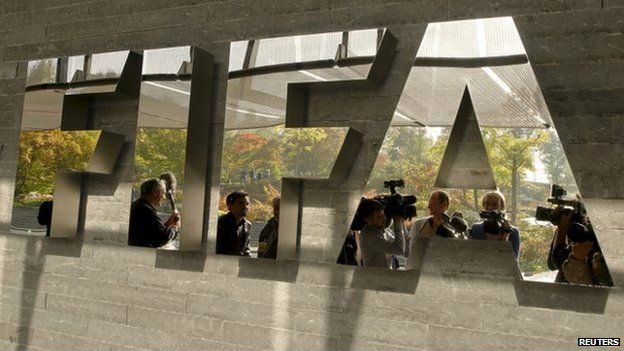 Journalists are reflected in a logo at the FIFA headquarters after a meeting of the executive committee in Zurich on 4 October 2013