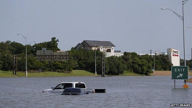 A car floating in water off of a highway in Texas