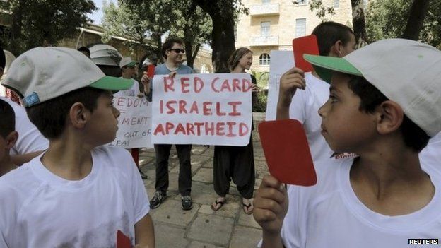 Palestinian children hold up red cards at a protest during a visit to the West Bank by Fifa president Sepp Blatter (19 May 2015)