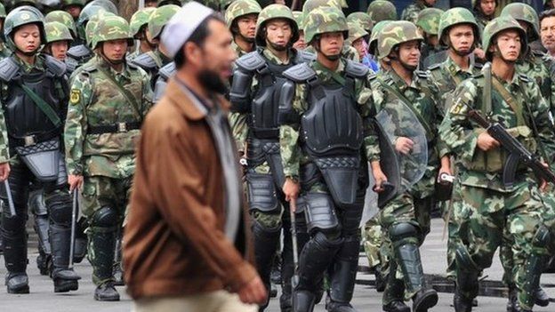 Armed Chinese soldiers march on patrol as a Uighur man crosses the street in Urumqi on July 15, 2009 in northwest China"s Xinjiang province