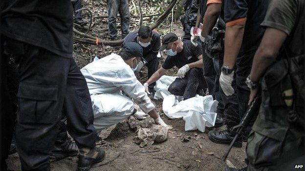 A Royal Malaysian Police forensic team handles exhumed human remains in a jungle at Bukit Wang Burma in the Malaysian northern state of Perlis, which borders Thailand, on May 26, 2015.