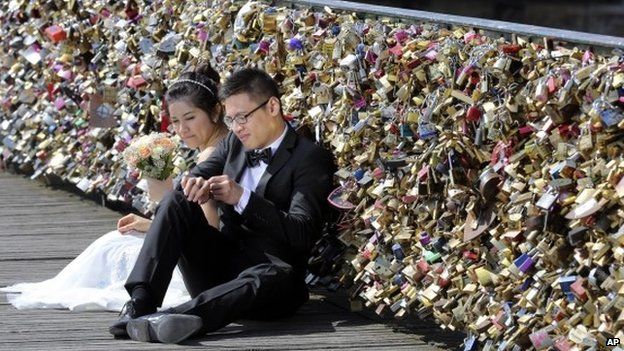 This Wednesday April 16, 2014 file photo shows a newly wed couple resting on the Pont des Arts in Paris, France