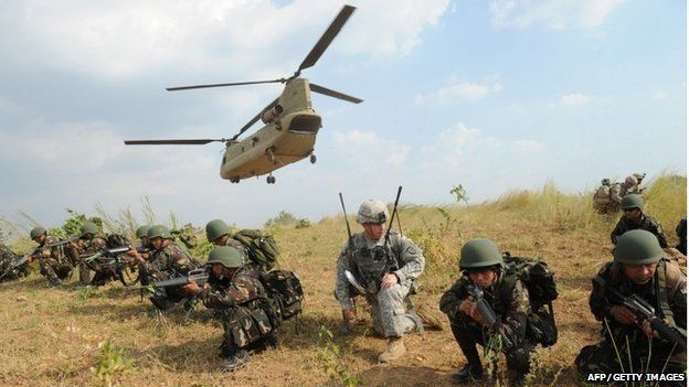 Philippine soldiers and a US army soldier from 2nd Stryker Brigade Combat of the 5th Infantry Division based in Hawaii take their positions after disembarking from a C-47 Chinook helicopter during an air assault exercise inside the military training camp of Fort Magsaysay in Nueva Ecija province north of Manila on April 20, 201
