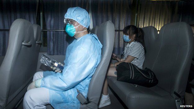 A health worker with protective suits sits with people who came into close contact with the Korean Mers patient in Hong Kong