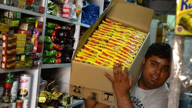 An Indian shopkeeper carries a box of "Maggi" noodles through his shop in Delhi on June 3, 2015