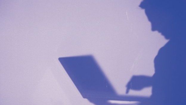 Man in silhouette looking at laptop