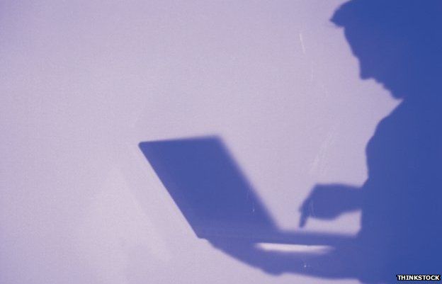 Man in silhouette looking at laptop