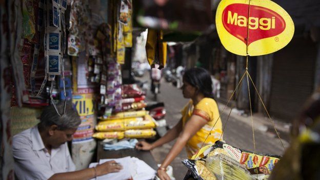 A basket filled with packaged food hangs with a 'Maggi' sign on it outside a shop in New Delhi, India, Wednesday, June 3, 2015.