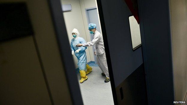 Medical personnel walk past inside the door of an ICU room at a hospital where a South Korean MERS patient is being quarantined and treated, in Huizhou, Guangdong province, China, June 1, 2015.