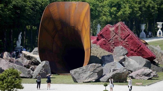People walk near Indian-born British artist Anish Kapoor"s "Dirty Corner" 2011 Cor-Ten steel, earth and mixed media monumental creation that is displayed in the gardens of the Chateau de Versailles, in Versailles, France, June 5, 2015.