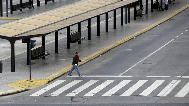 A pedestrian crosses an empty street during a 24-hour nationwide general strike