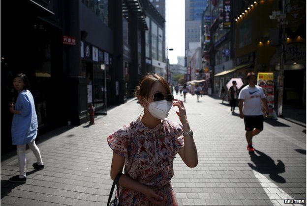 A tourist puts on a face mask to prevent contracting Middle East Respiratory Syndrome (MERS) at Myeongdong shopping district in central Seoul, South Korea, 10 June 2015