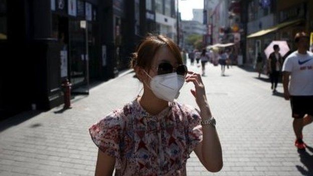 A tourist puts on a face mask to prevent contracting Middle East Respiratory Syndrome (MERS) at Myeongdong shopping district in central Seoul, South Korea, 10 June 2015